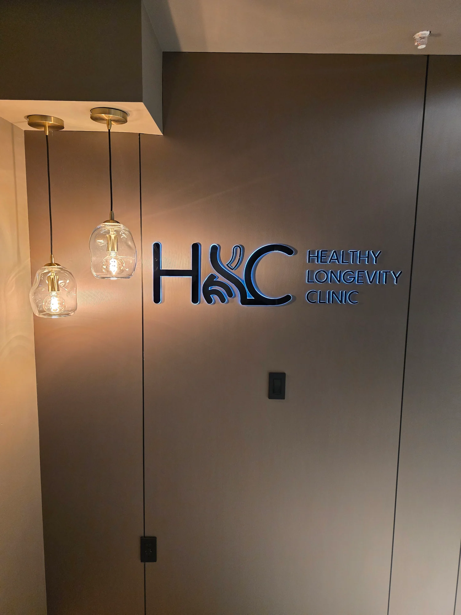 An illuminated HLC wall sign beside glass pendant lights.