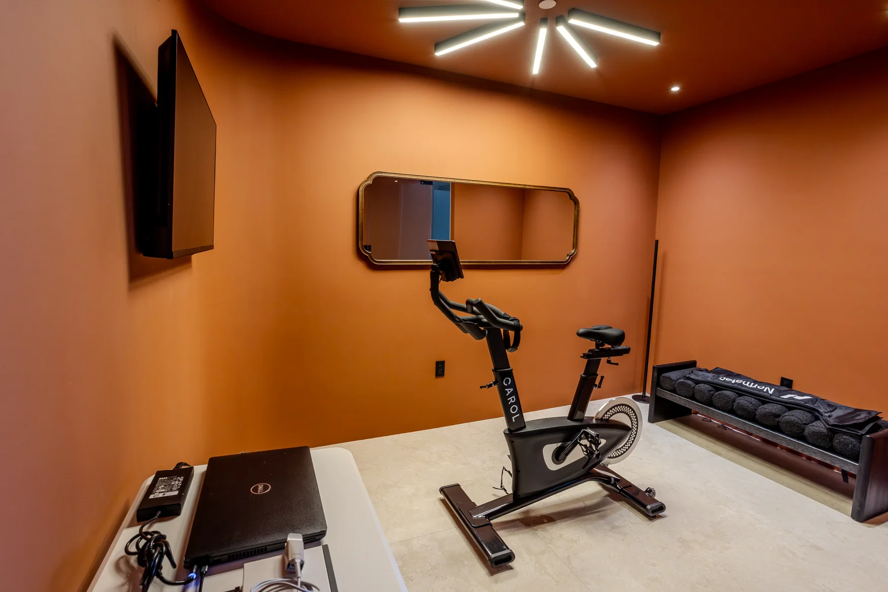 Terracotta-coloured room with an exercise bike, dumbbells and measurement equipment.