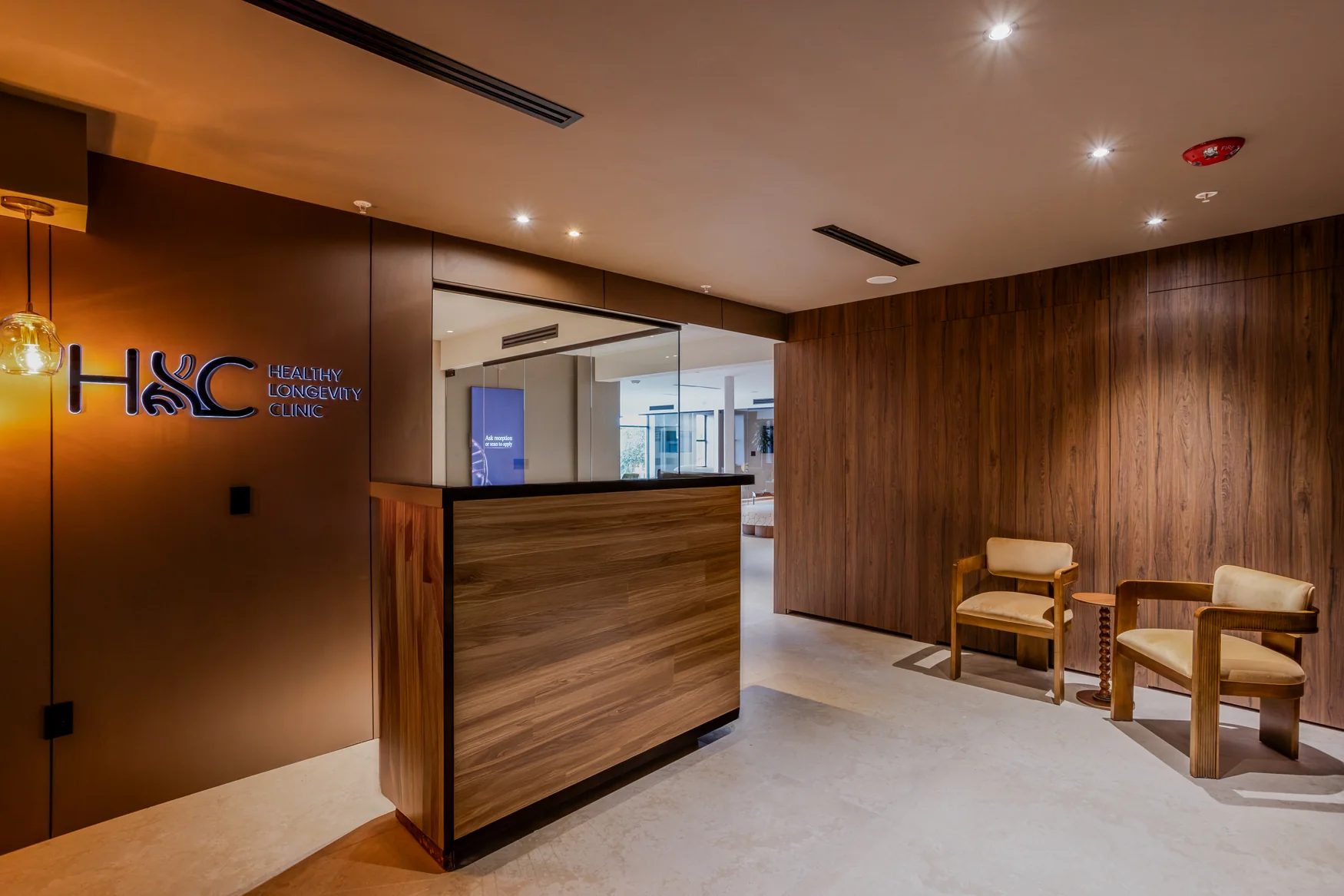 Wood-panelled reception desk, HLC wall logo and two chairs in the waiting area.