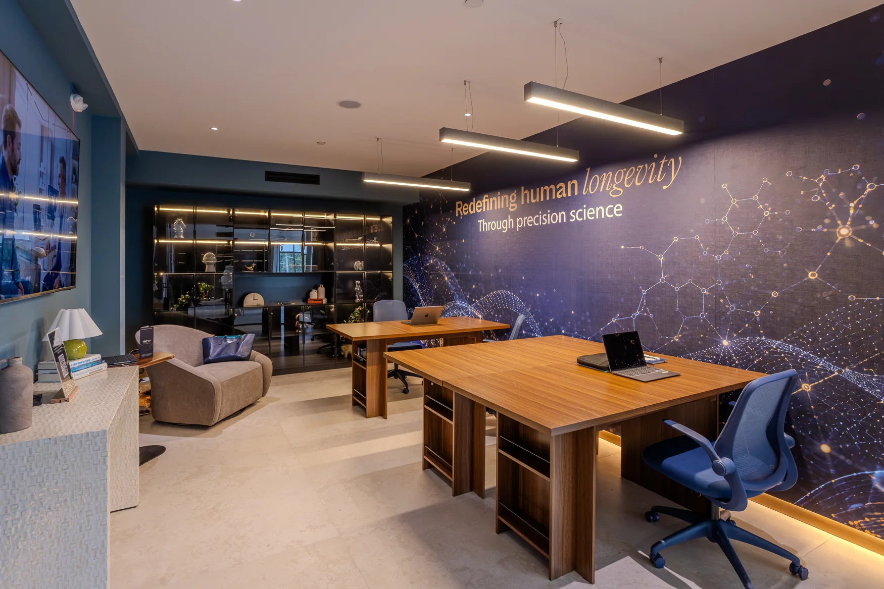Wooden desks and blue chairs beside a science-themed wall and a seating area.