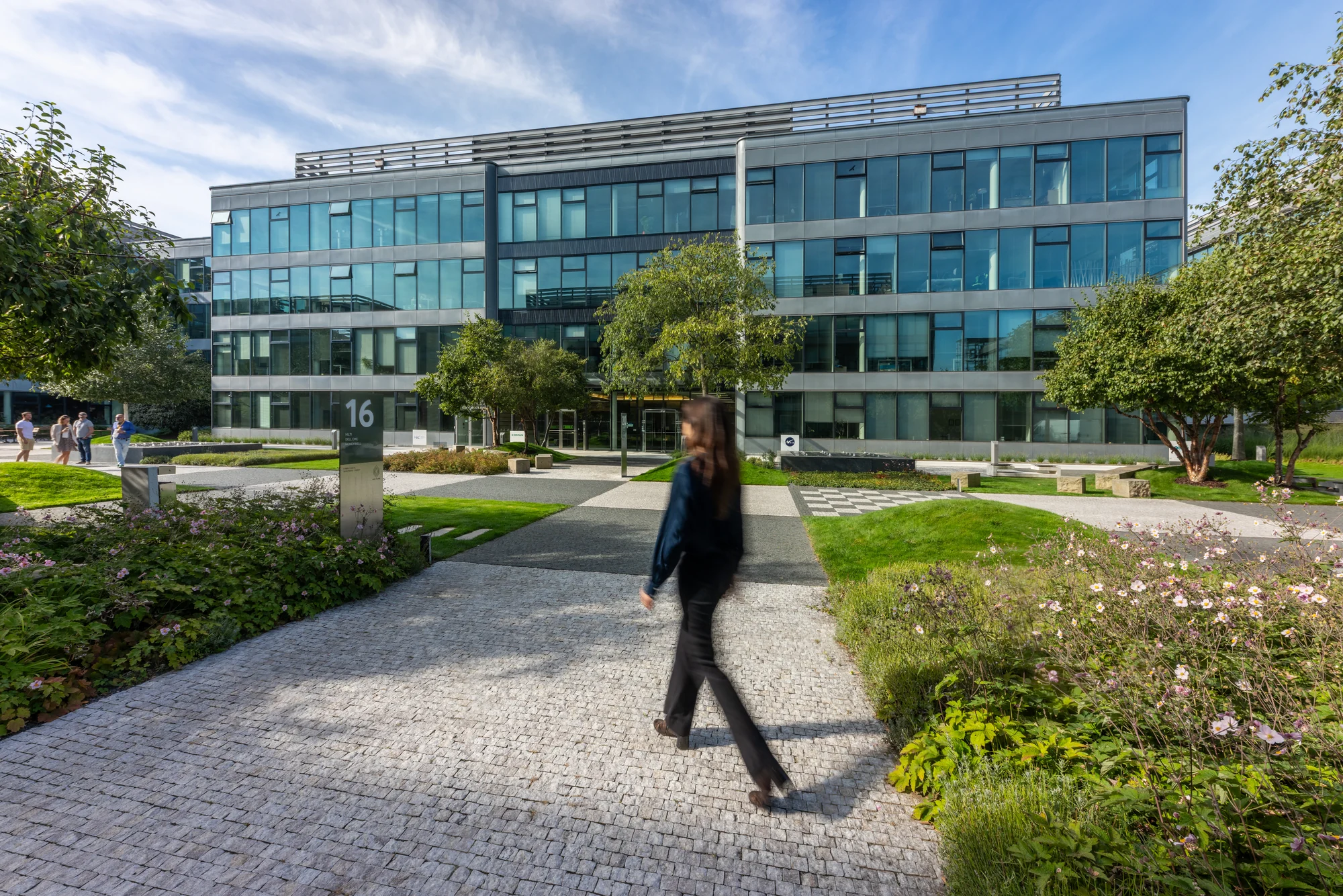 A glass-fronted building and landscaped pedestrian paths at The Park campus in Prague.