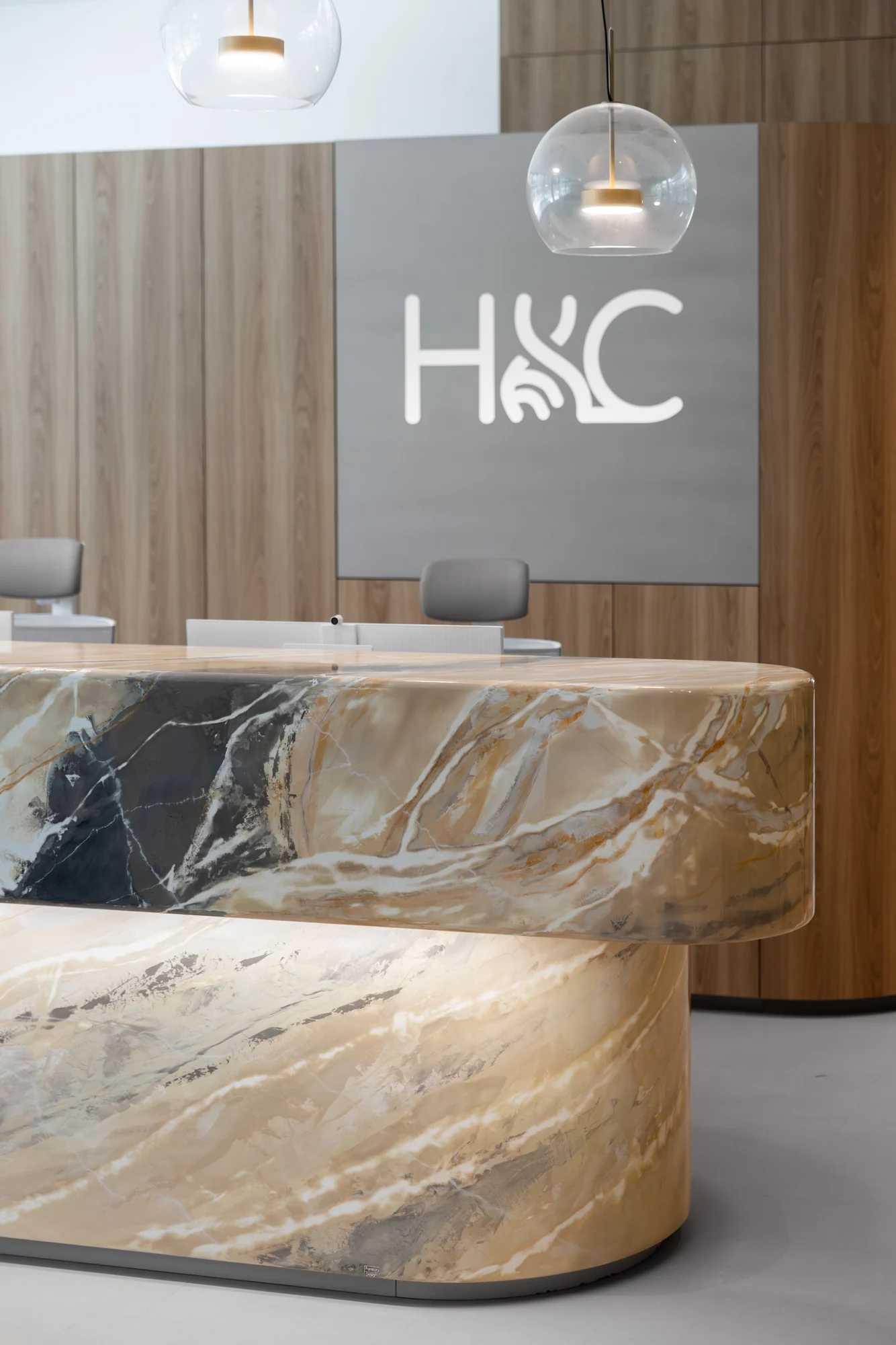 Close view of the curved reception counter beneath the HLC wall logo.